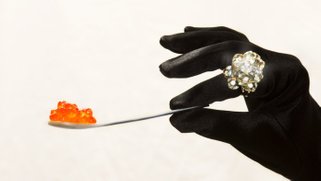 Artistic photo of a person's hand holding a spoon with a pile of gummy candies on it.